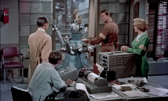 Dr. Zeitman (John Wengraf) shows off one of the robots in his computer room