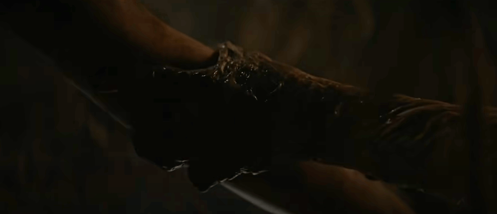 A creature's hand grabs Sarah's arm