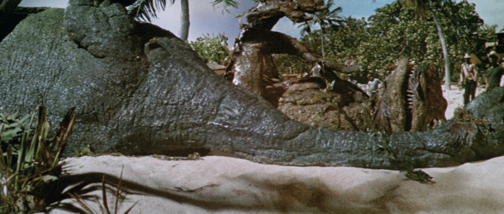 The inanimate bodies of the Brontosaurus and the Tyrannosaurus lie on the beach