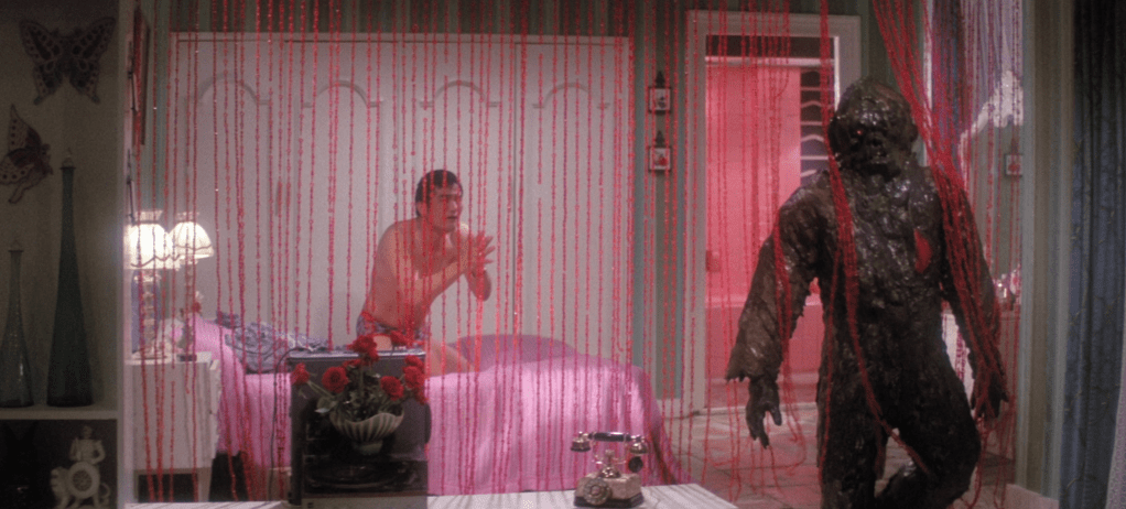 As a scared lover prays for mercy, the muddy monster paces away after killing his latest victim in her pink bathroom