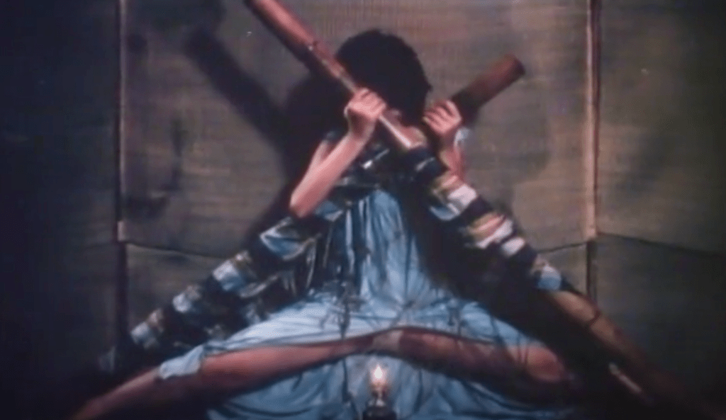 ...and she's forced by the bamboo poles to slowly lower down towards a lit oil lamp