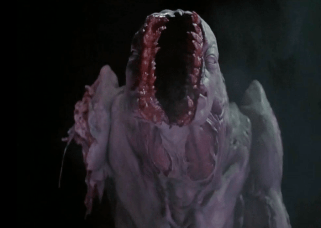 The split-faced creature loses an arm, but it keeps on fighting