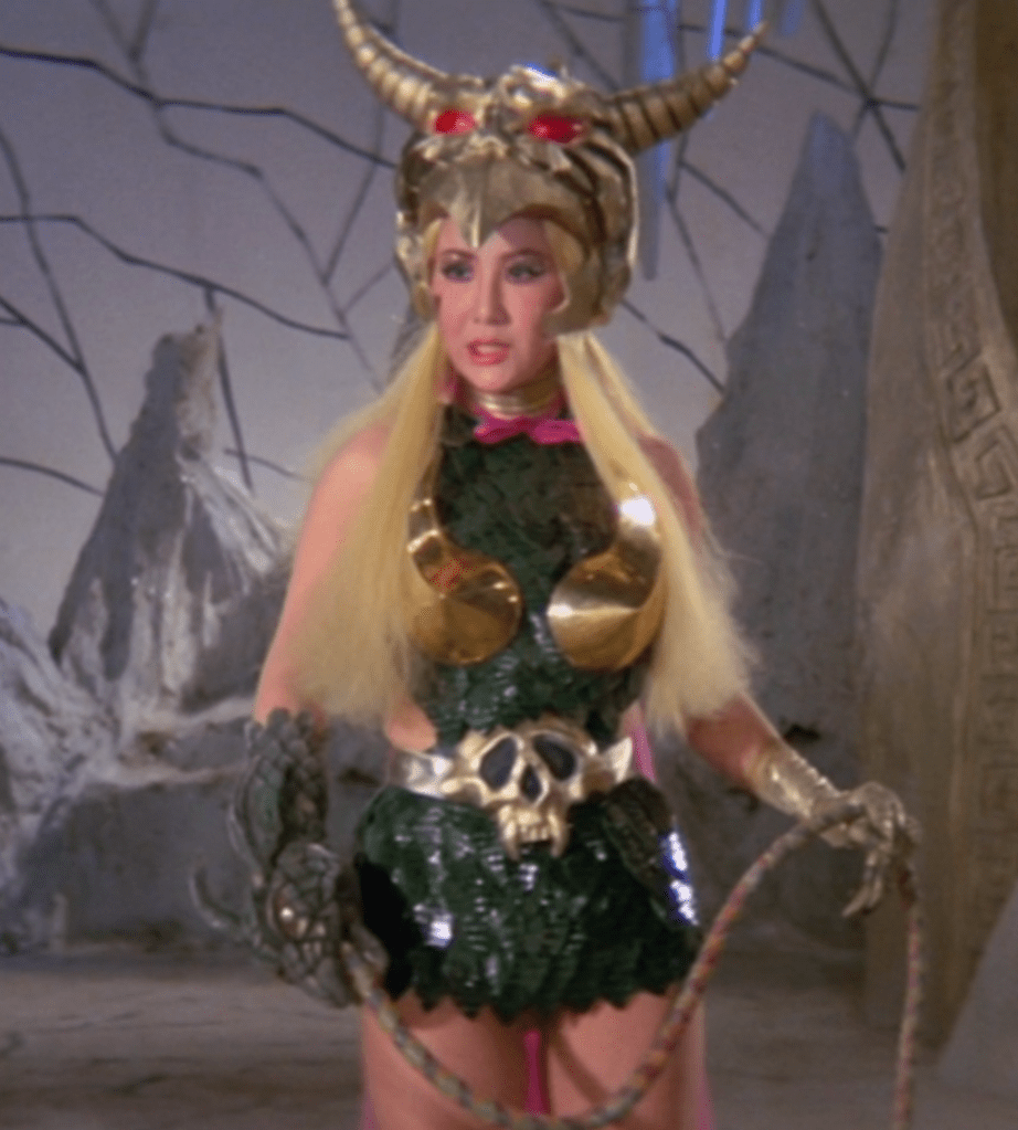 Princess Elzebub, wearing her special 'reptile head' glove, uses an electrified whip to fight Inframan during the finale