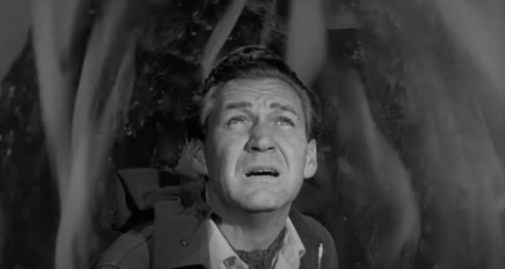 Alan Brooks (Tucker), with an alien burning away behind him