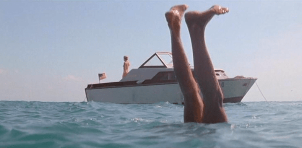 A dead victim is pulled through the water with his feet in the air