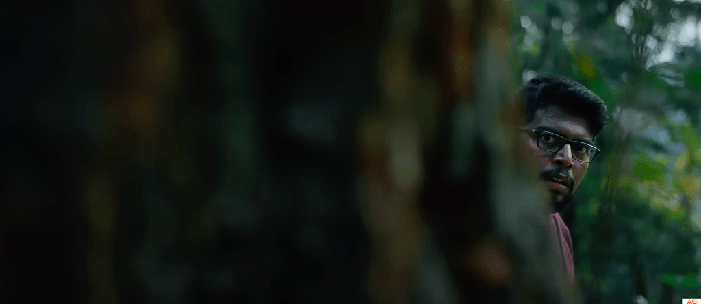 There are lots of shots of people peering around tree trunks