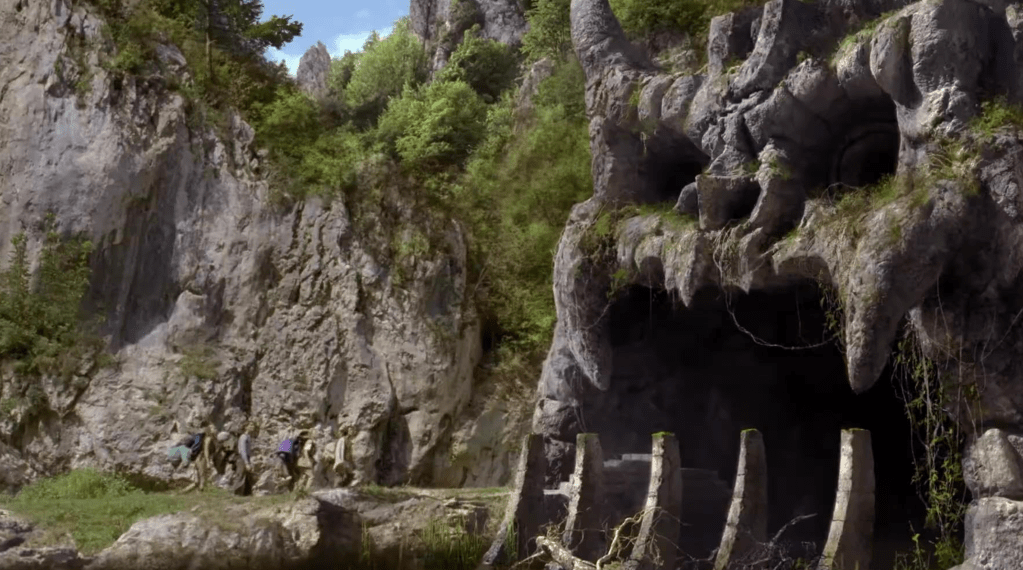 The explorers approach a skull-faced cave entrance in THE PRIMEVALS