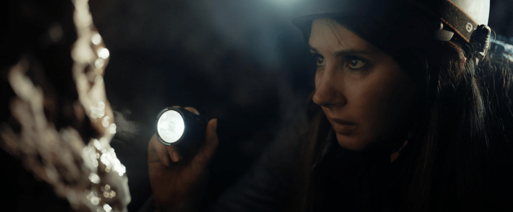 Sophia Eleni, who plays Nadia in BONE KEEPER, finds something glistening on the cave wall...