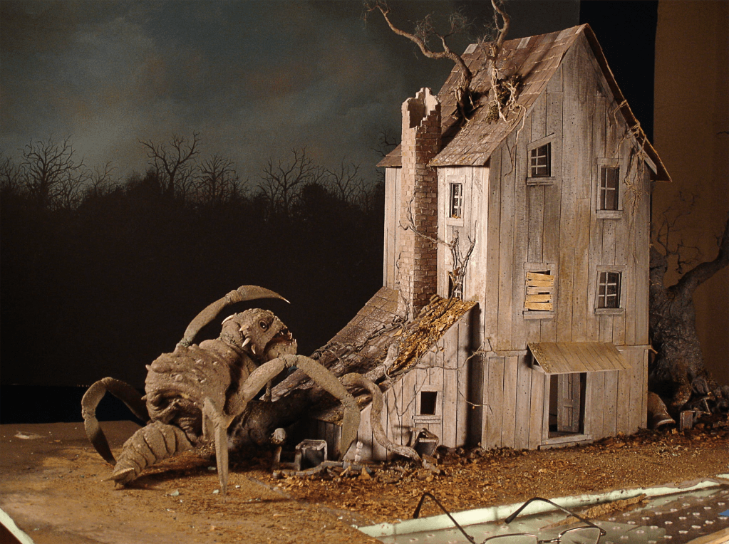 The reptile-bug-beast puppet and the wooden shack-building miniature